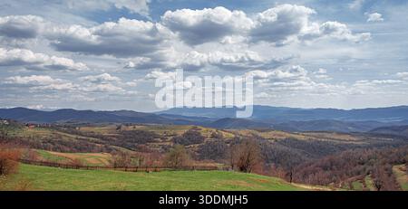 Un vasto paesaggio caratterizzato da colline ondulate e montagne lontane Foto Stock