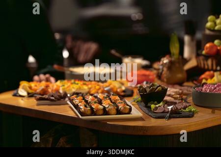Elegante buffet di catering con salmone affumicato, affettati e uova diavolate disposte su un tavolo di legno. Buffet per eventi di lusso con antipasti gourmet. Foto Stock