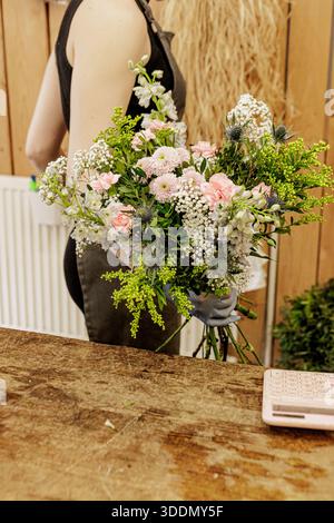 Fiorista che organizza un bouquet di fiori rosa e bianchi, festa della mamma Foto Stock