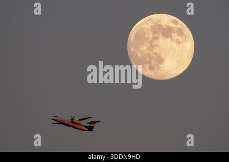 Londra, Regno Unito. 2 gennaio 2026. Meteo nel Regno Unito: Wolf Moon sorge sulla città. Un aereo passeggeri Luxair che decolla dall'aeroporto di Londra City passa davanti a una Luna Wolf quasi piena (98,7%), nota anche come Luna fredda, in quanto si alza nel tardo venerdì pomeriggio. Crediti: Guy Corbishley/Alamy Live News Foto Stock