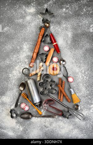 Un albero di Natale realizzato con utensili da forno delineati da farina spolverata, natura morta piatta per le vacanze. Foto Stock