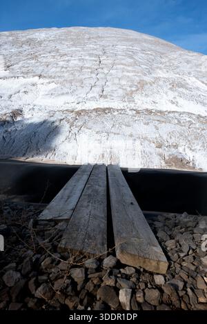 Una spettacolare prospettiva ad angolo basso mette in risalto un ponte in legno a tre assi che si estende su un profondo e scuro specchio d'acqua o un laghetto industriale. Poll Foto Stock