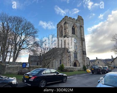 Edificio storico in pietra della chiesa All Saints nel villaggio di Rothbury in Inghilterra con navata, torre e dettagli architettonici. Foto Stock