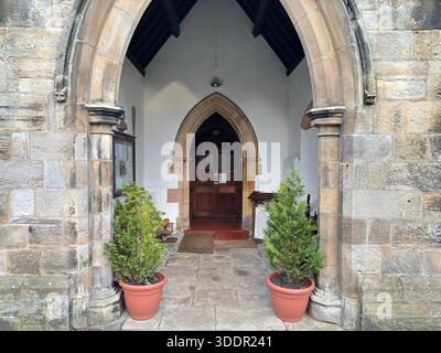 Edificio storico in pietra della chiesa All Saints nel villaggio di Rothbury in Inghilterra con navata, torre e dettagli architettonici. Foto Stock