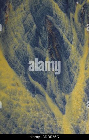 Vista aerea del sistema fluviale intrecciato con un arazzo di sedimenti d'oro che fluiscono nelle acque scure e ghiacciate dell'Islanda meridionale e dell'Islanda. Foto Stock