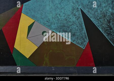 BERLINO-Germania-17 aprile 2025, opera geometrica astratta in rosso, giallo e blu su una sezione dello storico muro di Berlino, conservata come lato est Foto Stock