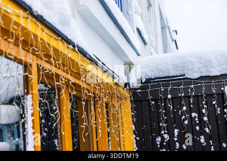 Vista ravvicinata della telecamera di sicurezza ad energia solare montata sulla facciata della villa con luci garland appese in inverno. Svezia. Foto Stock