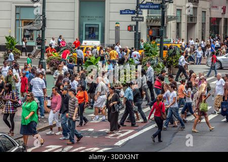 La folla si sposta attraverso l'intersezione tra la 6th Avenue e la 34th Street a Midtown Manhattan, uno dei corridoi pedonali più attivi di New York. Foto Stock