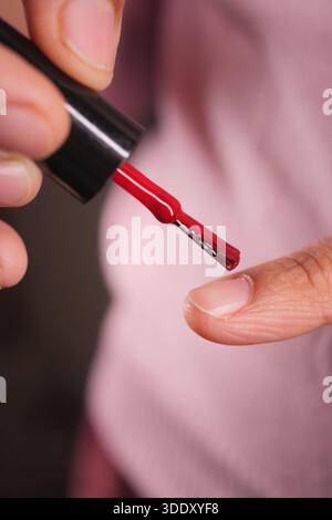 Tinteggiatura di unghie con lucidatura rossa in vista ravvicinata Foto Stock