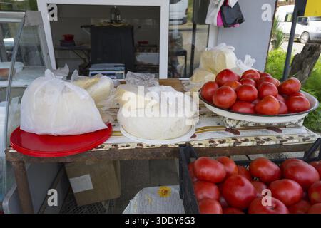 Un bancone con pomodori e formaggio, freschi e su piatti e avvolti in plastica, che vende formaggio e pomodori, Badiauri, regione di Kakheti, Georgia Foto Stock