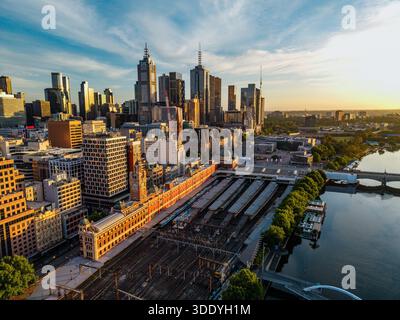 Una prospettiva aerea cattura il quartiere centrale degli affari di Melbourne durante l'ora d'oro, con la stazione di Flinders Street, i grattacieli e lo Yarra Foto Stock