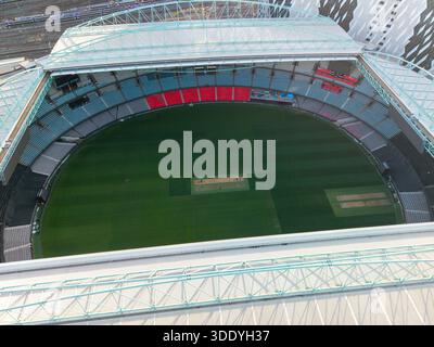 Una vista aerea cattura uno stadio polisportivo vuoto, mostrando il suo vivace campo da gioco verde, file di posti a sedere colorati e la rete ferroviaria adiacente. Foto Stock