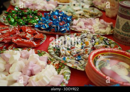 Un vivace assortimento di caramelle, cioccolatini e marshmallow serviti su piatti di carta festivi. Perfetto per i temi della festa della comunità Foto Stock