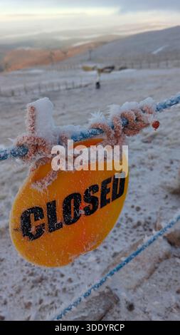 Un cartello CHIUSO coperto di ghiaccio su un pendio innevato nelle Highlands scozzesi, che cattura le dure condizioni invernali e la quiete di un paesaggio ghiacciato Foto Stock