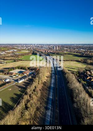 Vista aerea sull'autostrada M621 verso lo skyline del centro di Leeds, con cintura verde circostante e alloggi periferici nel West Yorkshire, Regno Unito Foto Stock