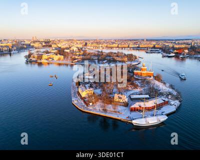 Una vista aerea con drone delle isole storiche di Kastellholmen e Skeppsholmen coperte di neve durante un'alba invernale a Stoccolma, Svezia. Foto Stock