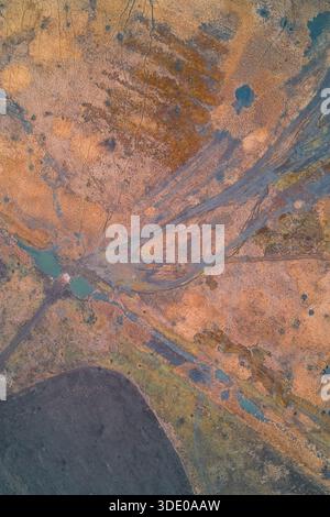 Una vista aerea geometrica astratta delle superfici del terreno. La composizione è caratterizzata da linee dritte e blocchi di colore, vegetazione verde a contrasto con terreno marrone, ideale per l'uso come sfondo agricolo strutturato. Foto Stock