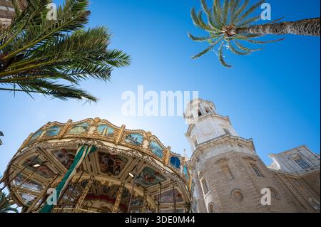 Torre della Cattedrale di Cadice vicino alla giostra nostalgica. Vista ad angolo basso Foto Stock