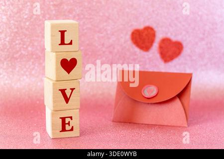 Sfondo romantico. Una busta rossa con una dichiarazione d'amore, il cuore di Valentine. Una dichiarazione d'amore alla persona più vicina. La parola AMORE sul legno Foto Stock
