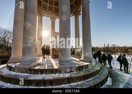 Die tiefstehende Wintersonne strahlt durch die Säulen des monopteros, ein klirrend kalter Wintertag im Englischen Garten, Sonntag, München, Januar 2026 Deutschland, München, Januar 2026, monopteros im Englischen Garten, viele Menschen genießen den strahlend schönen Wintertag im Park, Die tiefstehende Wintersonne strahlt zwischen den Säulen des monopteros, Blick vom monopteros auf den malerisch verschneiten Park, am Horizont die Stadtsilhouette, Sonntagnachmittag, frostige che Temperland, Winterluft, Winterluft, Winterluft, Winterluft 4 Graftsilhouette, Winterluft, Winterluft, Winterluft, Winterluft, Winterlend, Kälte Winterhimmel, Architektur, Bayern, *** il basso Foto Stock