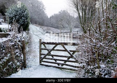 Cancello di legno aperto che conduce al sentiero in un paesaggio di campagna innevato nella campagna gallese Carmarthenshire Dyfed gennaio 2026 Regno Unito KATHY DEWITT Foto Stock
