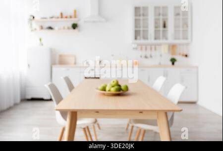Foto sfocata della cucina classica scandinava con dettagli in legno e bianco. Tavolo da pranzo e mobili leggeri Foto Stock