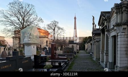 Le persone visitano il cimitero di Passy, Parigi, esplorando le lapidi e i monumenti durante il tramonto. La Torre Eiffel è visibile sullo sfondo, aggiungendo Foto Stock