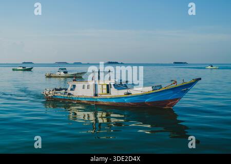 Balikpapan, Indonesia - 8 novembre 2025. Una tradizionale barca da pesca indonesiana di medie dimensioni, dipinta con colori vivaci, con una cabina bianca e uno scafo blu Foto Stock