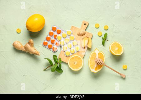 Tosse gocce in blister con limoni, foglie di menta e radice di zenzero su sfondo verde Foto Stock
