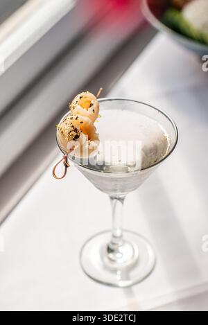 Elegante cocktail martini al litchi servito in un classico bicchiere di martini, con vodka, liquore al litchi e succo di litchi. Foto Stock