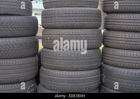Pile di pneumatici per veicoli in gomma nera con telaio stretto fotografate a distanza ravvicinata. Scanalature del battistrada dettagliate e usura della superficie visibili. Foto Stock