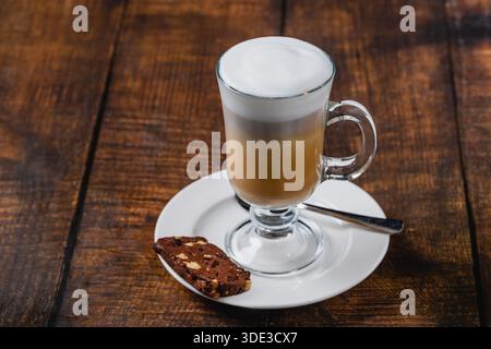 Latte macchiato con latte a strati e schiuma su un tavolo di legno Foto Stock