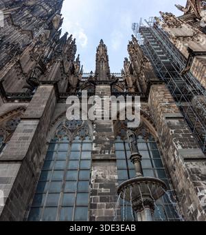 COLONIA, GERMANIA - 31 MAGGIO 2024: Guglie gotiche ornate e contrafforti della cattedrale di Colonia contro un cielo blu. Vista dal basso che mostra la fossa del restauro Foto Stock