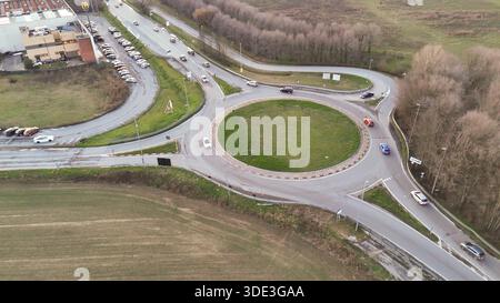 Una prospettiva dall'alto cattura i veicoli che si muovono attraverso una rotatoria a più corsie, mostrando le infrastrutture urbane e le dinamiche dei trasporti Foto Stock