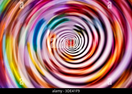 fotografia astratta caratterizzata da un vivace e vorticoso motivo di cerchi concentrici con un mix di colori vivaci, tra cui rosso, rosa, blu, verde e a te Foto Stock