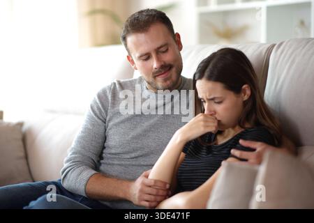 Amico tossico e falso essere felice con il dolore femminile seduto su un divano a casa Foto Stock