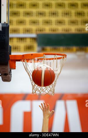 una mano getta un pallacanestro in un cesto Foto Stock