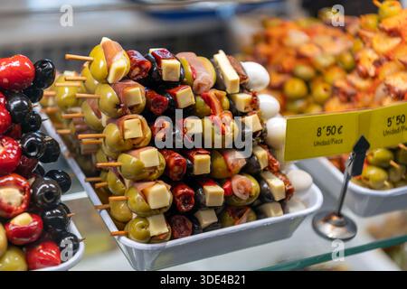 Madrid, Spagna - 15 ottobre 2025: Spiedini gourmet di olive e formaggi (banderillas) in un mercato di tapas. Foto Stock