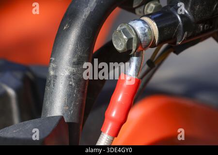Immagine ravvicinata del manubrio nero per motociclette con manicotto di protezione cavo rosso che mostra una meccanica robusta e un lucente bullone in metallo cromato su un potente BI Foto Stock