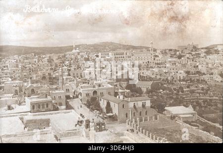 Da una raccolta mista di cartoline di storia sociale. Un panorama di Betlemme in tonalità seppia del 1919 mostra edifici in pietra con tetti piani e cupole raggruppati su terreni collinari. Chiese e moschee sorgono tra la densa architettura, incorniciate da colline ondulate. L'immagine cattura il patrimonio religioso stratificato della città e la forma urbana dell'inizio del XX secolo. Foto Stock