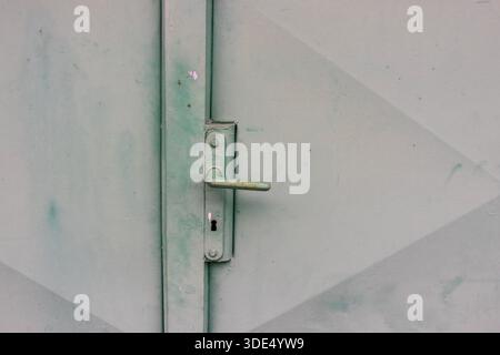 Maniglia della portiera in metallo verde resistente agli agenti atmosferici e foro per chiave con vernice usurata e texture industriale Foto Stock