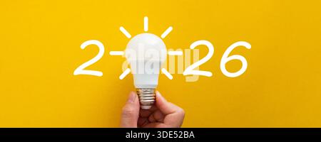 Mano che regge una lampadina luminosa come zero nel 2026, simboleggiando nuove idee e innovazioni Foto Stock