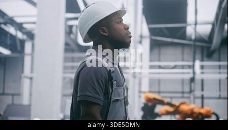 Focused Factory Engineer fornisce sistemi industriali di monitoraggio professionali in elmetto e tute di sicurezza con espressione seria. Responsabilità concettuale per il monitoraggio di sistemi industriali complessi. Foto Stock