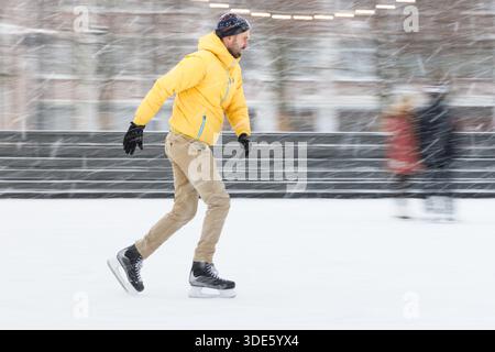 Uomo barbuto di mezza età sulla pista di pattinaggio su ghiaccio, all'aperto nelle giornate invernali innevate Foto Stock