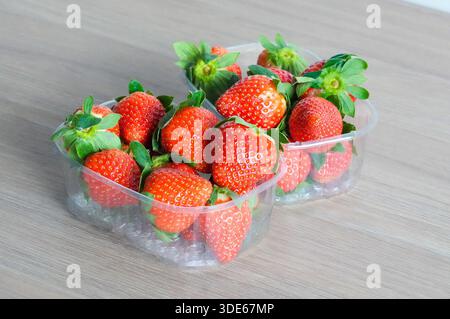 Fragola in scatola di plastica su sfondo tavolo in legno, foto stock Foto Stock