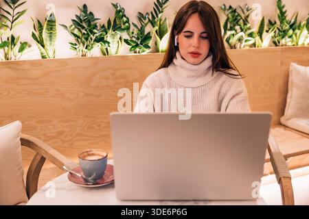 Giovane donna che lavora in remoto con un notebook in un bar Foto Stock