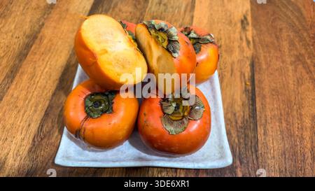 i cachi organici sono disposti sul piatto con una fetta aperta Foto Stock
