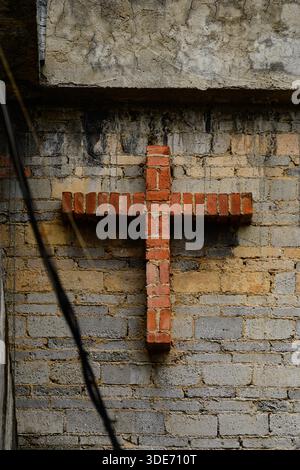 The solemn cross of the Catholic Church rises above the stone rooftops of Qingyan Ancient Town. Foto Stock