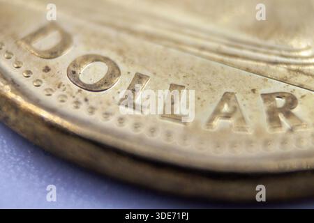 Macro primo piano della moneta canadese Loonie che mostra l'iscrizione in dollari - dettaglio valuta Canada One Dollar Foto Stock