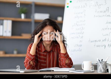 Annoiato e stanco insegnante toccare templi che soffrono di mal di testa Foto Stock